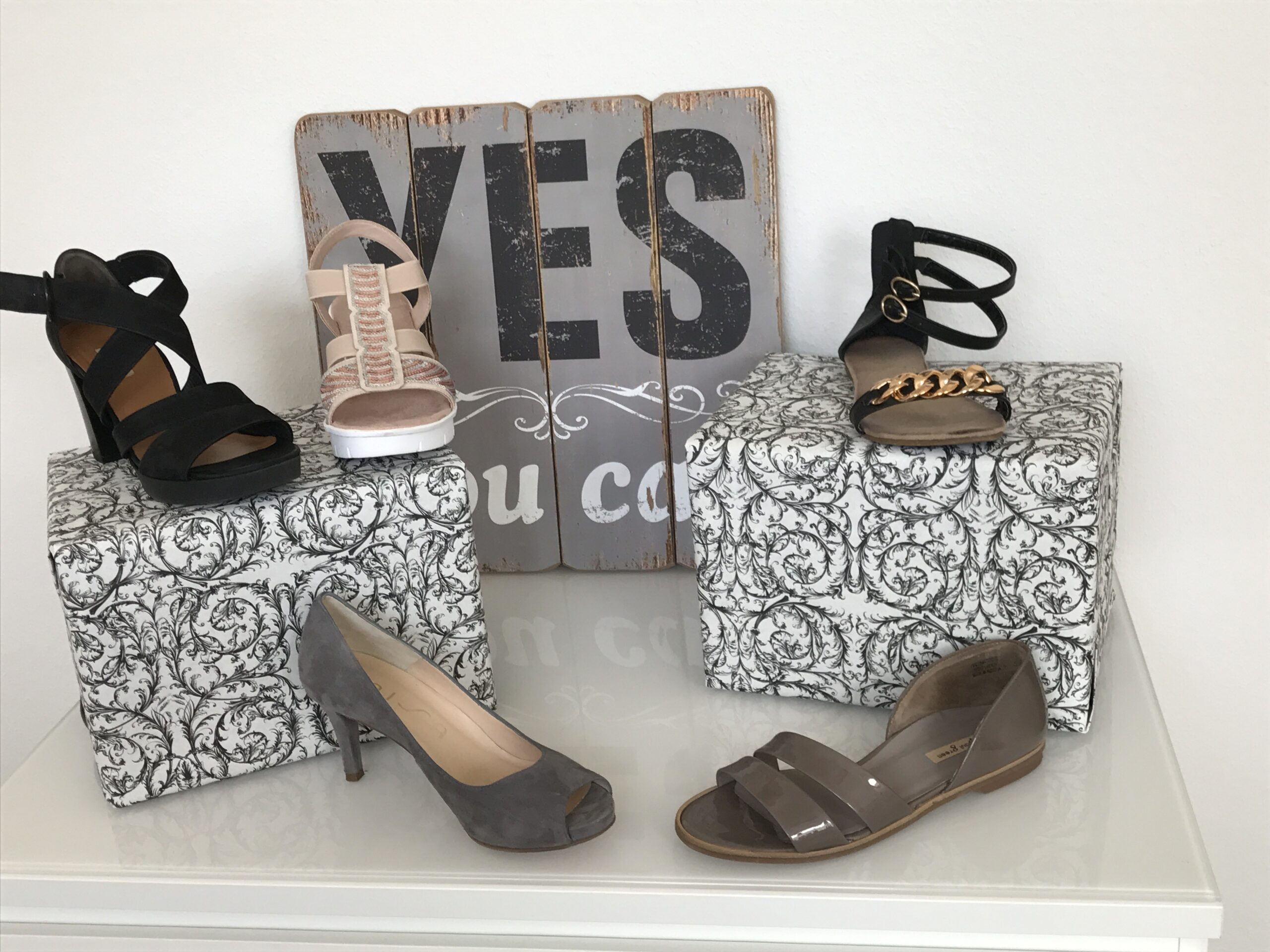 Verschiedene Sandaletten. Im Hintergrund der Spruch:"Yes, you can".